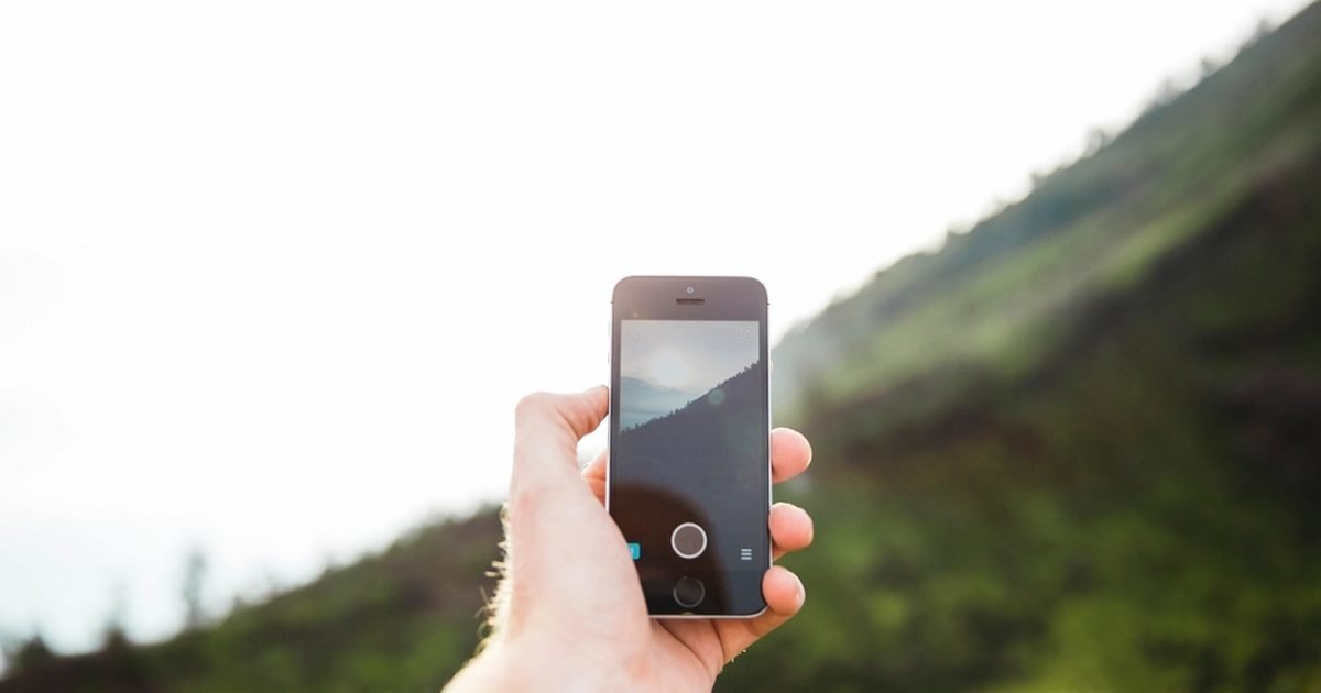 Hand holding a phone outdoors, representing location permission checks