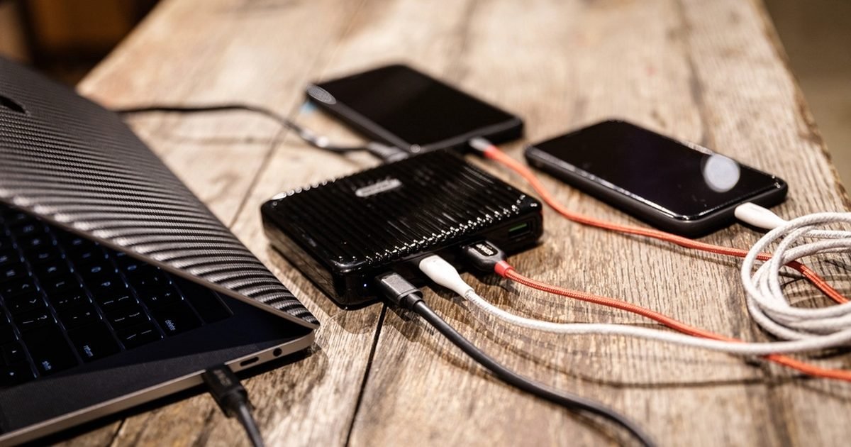 Phones and a laptop charging from a shared power bank on a table