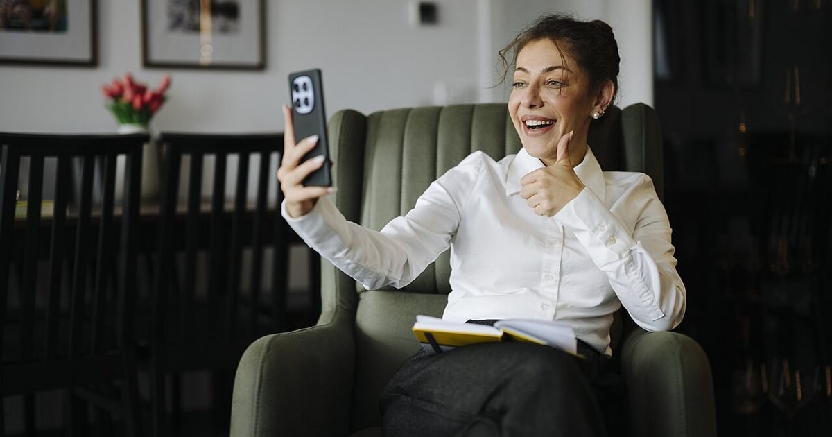 Woman smiling while using a smartphone for a video call at home