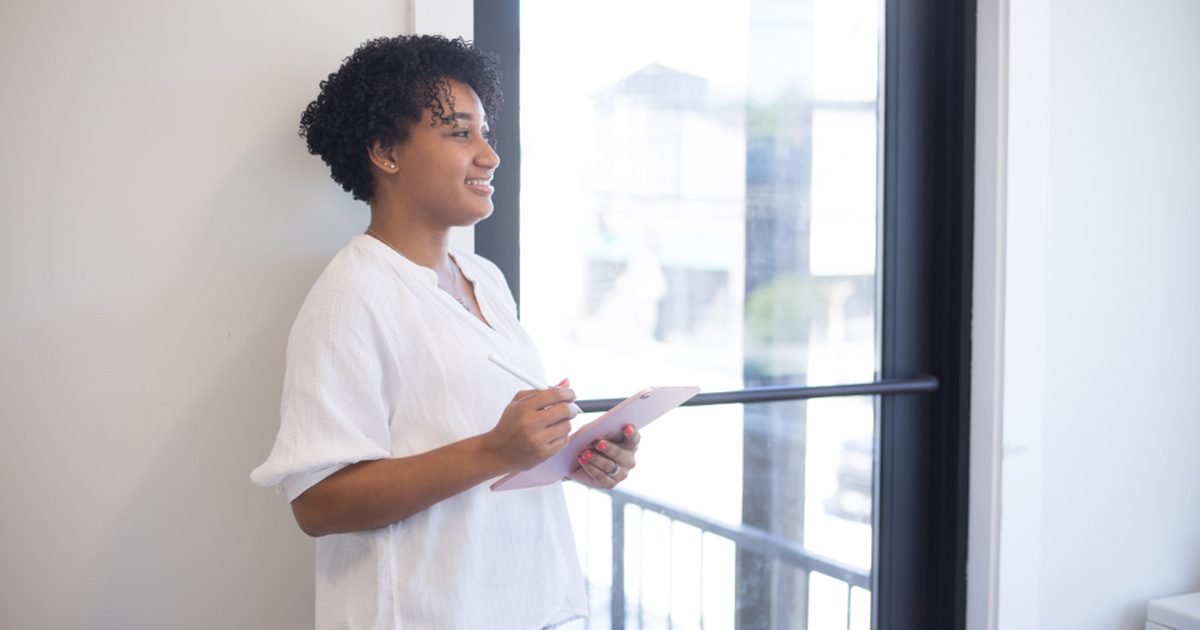 Person holding a tablet near a window while considering screen size and portability
